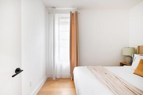 a white bedroom with a bed and a window at 403-3C Newly renovated 3br in prime UES in New York