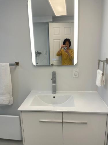 a woman taking a picture of a sink in a bathroom at Rose Garden Vancouver in Richmond