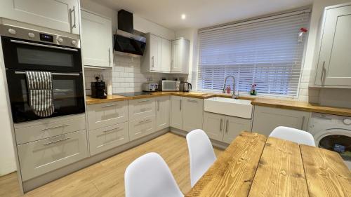 a kitchen with a wooden table and white cabinets at COSY Modern HOME Euston Fitzrovia in London
