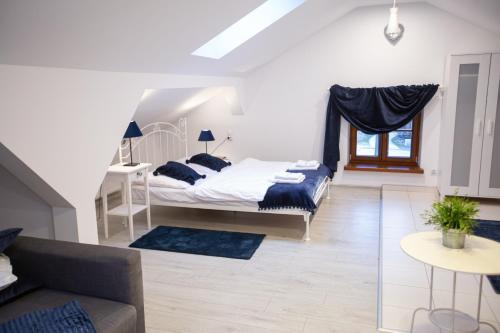 a white bedroom with a bed and a couch at Apartamenty Stacja Kasina in Kasina Wielka