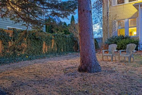 two chairs sitting next to a tree next to a house at Charming Belmont Condo Near Boston condo in Belmont