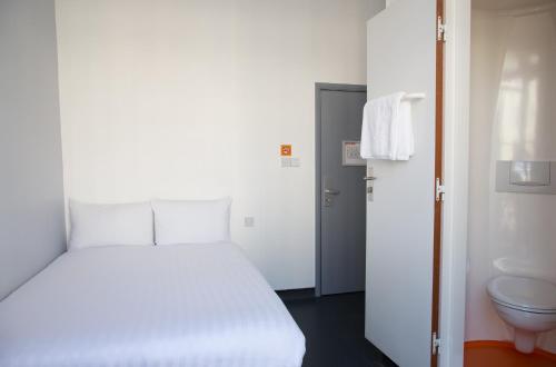 a bedroom with a white bed and a toilet at easyHotel Victoria in London