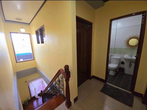 a hallway with a bathroom with a toilet and a staircase at NOBER Apartments in Puerto Princesa City