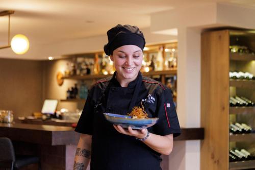 a woman holding a bowl of food in a restaurant at Senda Monteverde Hotel Member of the Cayuga Collection in Monteverde Costa Rica