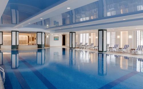 a large swimming pool in a building with chairs at Shamakhi Palace Sharadil in Şǝrǝdil
