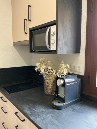 a kitchen counter with a microwave and a vase of flowers at Monasteriohome pt2 in Ibdes