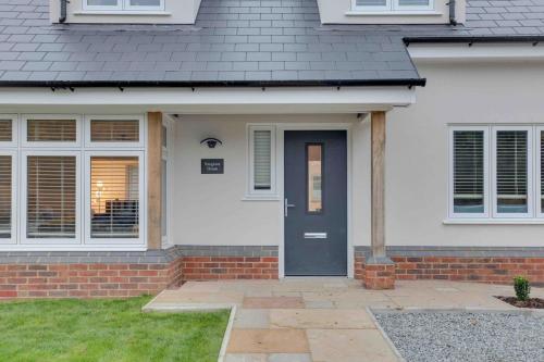 a white house with a blue door and a yard at Foxglove House & Hot Tub Stansted Airport in London Stansted Airport