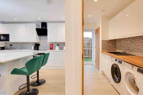 a kitchen with a washing machine and a green chair at Foxglove House & Hot Tub Stansted Airport in London Stansted Airport