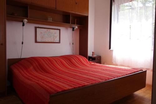 un lit dans une chambre avec une couverture rouge dessus dans l'établissement Apartments Nev, à Blato