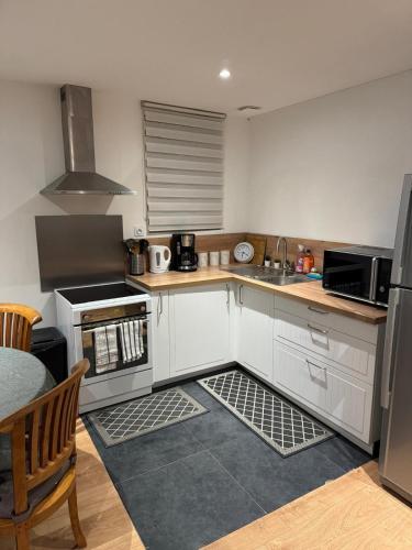 une cuisine avec des armoires blanches et un four à plaques de cuisson dans l'établissement Spacieux duplex avec parking privé, à Wattignies