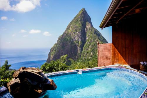 a swimming pool with a mountain in the background at Ladera Resort in Soufrière