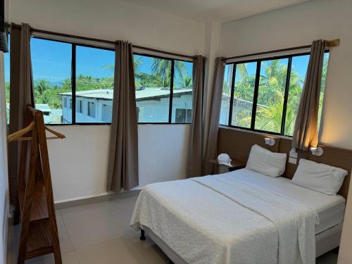 a bedroom with a bed and two large windows at Hotel Paseo del Sol in La Paz