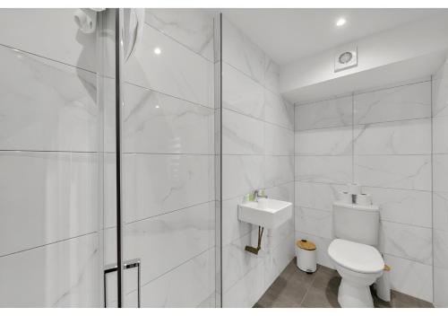 a white bathroom with a toilet and a shower at Escape the Ordinary: Cozy and Charming Studio in London
