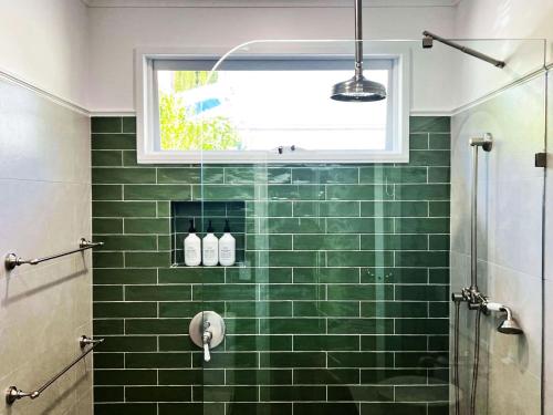 a bathroom with a green tiled shower with a window at Sausalito- captivating 1950s retro residence in Daylesford