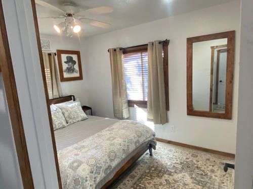a bedroom with a bed and a mirror and a window at Zion to Bryce cowboy cabin in Hatch