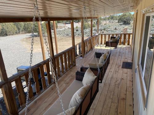 a porch with couches on a porch swing at Zion to Bryce cowboy cabin in Hatch