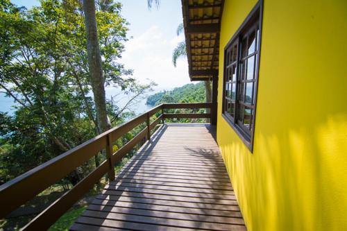 a yellow building with a wooden walkway with a window at Cabanas Do Araçá Villa in Porto Belo