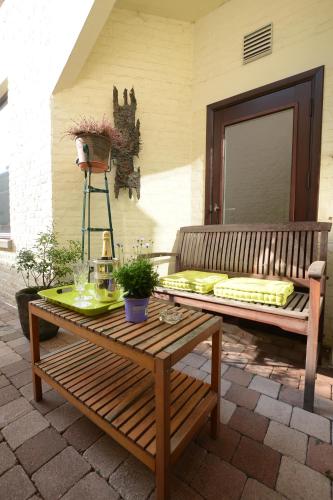 a wooden bench sitting on a patio with a table at R&breakfast in Roeselare