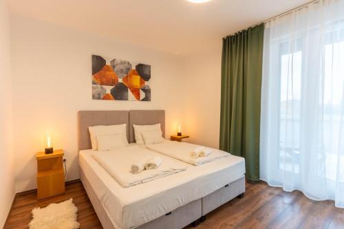 a bedroom with a bed and a large window at Lakeview Apartment Fonyód in Fonyód