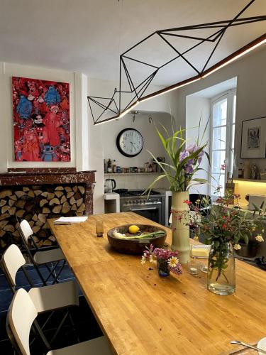 une cuisine avec une table en bois fleurie et une horloge dans l'établissement Artist Residence - courtyard, terrace, Grand Piano, à Siran