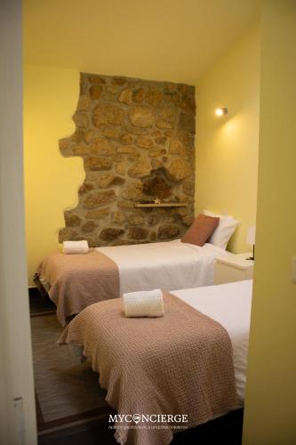 a hotel room with two beds and a stone wall at Quinta Do Larai in Vale de Cambra