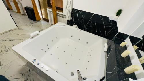 a white tub in a bathroom with black tiles at Hedonist Spa Jacuzzi Sarajevo Free parking in Sarajevo