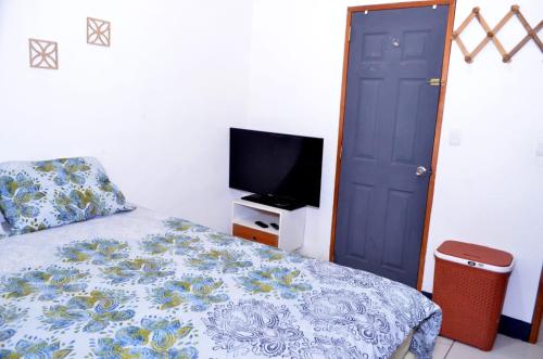 a bedroom with a bed with a tv and a blue door at Casa Sunshine in Matagalpa