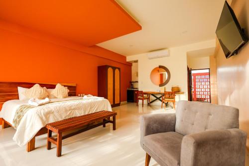 a bedroom with orange walls and a bed and a chair at Hotel Wellness - Belleza y Serenidad in Boca del Río