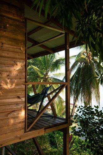 a hammock in a wooden building with palm trees at Ponci’s Gate to Gaia Holistic Center in Bocas del Toro