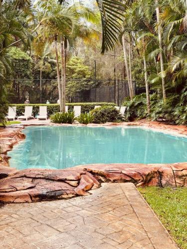 a large swimming pool with a rock around it at Paradise Palms at Aanuka Resort Diggers Beach Quiet Villa in Coffs Harbour