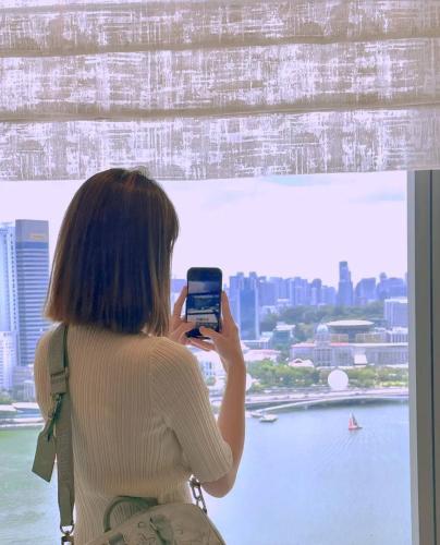 a woman taking a picture of the water with her cell phone at 夜色V8s in Kampong Alor Gajah
