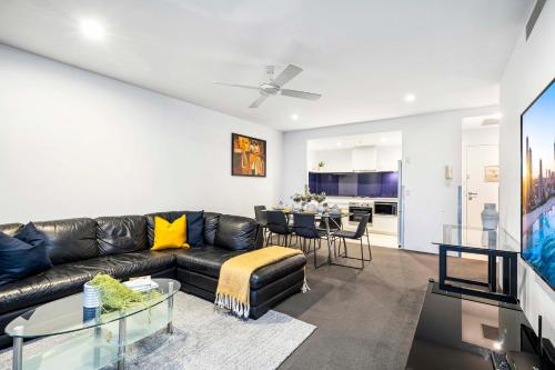 a living room with a black leather couch and a table at Circle on Cavill - Self Contained & Privately Managed - Wow Stay in Gold Coast