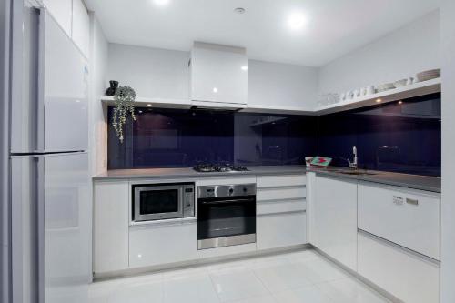 a kitchen with white cabinets and a stove top oven at Circle on Cavill - Self Contained & Privately Managed - Wow Stay in Gold Coast