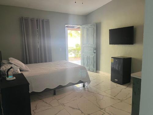 1 dormitorio con 1 cama, TV y puerta en Boni Beach, en Miravalles