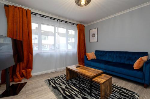 a living room with a blue couch and a table at Cozy 2-Bed Detached Bungalow with Parking Woking in Horsell