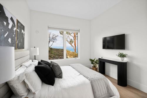 a white bedroom with a large bed and a window at Mountain Suite, Ocean View Fire Pit, Fully Equipped Kitchen, WD in Nanaimo