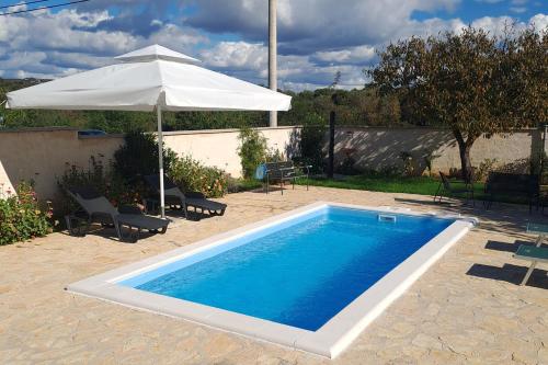 a swimming pool with a white umbrella and an umbrella at Family friendly house with a swimming pool Dazlina, Sibenik - 23303 in Tisno