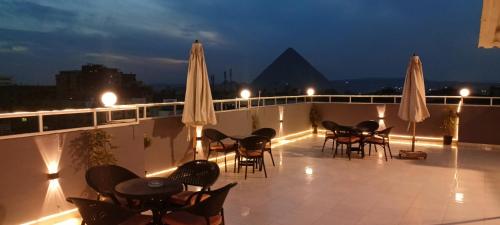 a balcony with chairs and tables and umbrellas at night at Phoenix Pyramids View Inn in Cairo