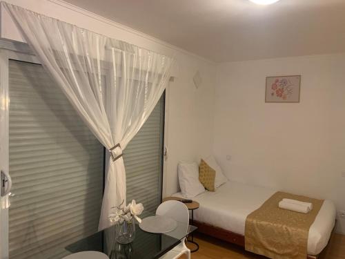 a small bedroom with a bed and a window at Charming Studio with Balneo Shower, Parking Included in Brétigny-sur-Orge