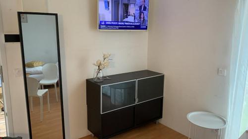 a living room with a television and a mirror at Charming Studio with Balneo Shower, Parking Included in Brétigny-sur-Orge