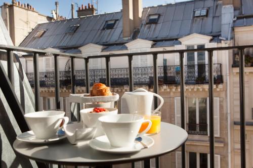a table with cups of coffee on a balcony at Hotel La Lanterne & Spa By Timhotel in Paris