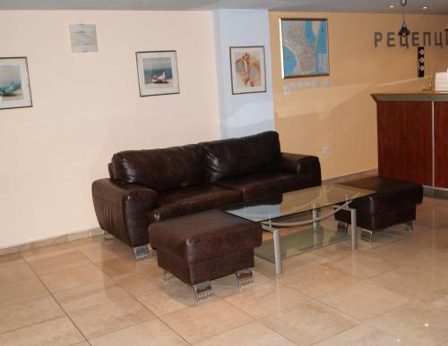 uma sala de estar com um sofá de couro e uma mesa de vidro em Hotel Fors em Burgas
