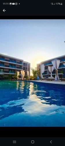 a picture of a swimming pool in front of a building at Malia Beach 302 D - Muro Alto - Porto de Galinhas in Porto De Galinhas