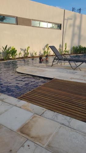 a swimming pool with a chair next to a building at Malia Beach 302 D - Muro Alto - Porto de Galinhas in Porto De Galinhas