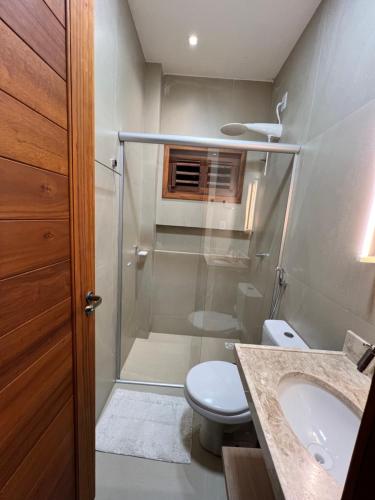 a bathroom with a shower and a toilet and a sink at Chalé Encantador com Rooftop Privativo in Cajueiro