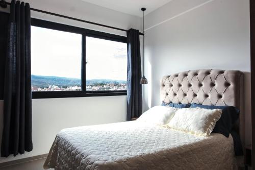 ein Schlafzimmer mit einem Bett mit einem großen Fenster in der Unterkunft El mirador, moderno y acogedor departamento con balcon privado in Tarija