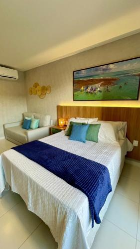 a bedroom with a large bed and a couch at Malia Muro Alto - Porto de Galinhas - Flat para 5 pessoas vista piscinas in Ipojuca