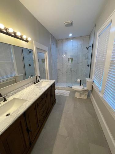 a bathroom with two sinks and a toilet and a shower at Sparkle City Cottage in Spartanburg