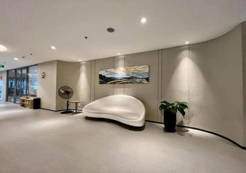 a living room with a white chair and a plant at The Song Boutique Apartment in Vung Tau
