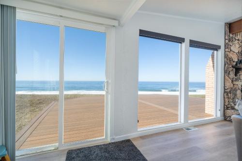 a living room with sliding glass doors looking out at the ocean at Inlet Cottage in Lincoln City